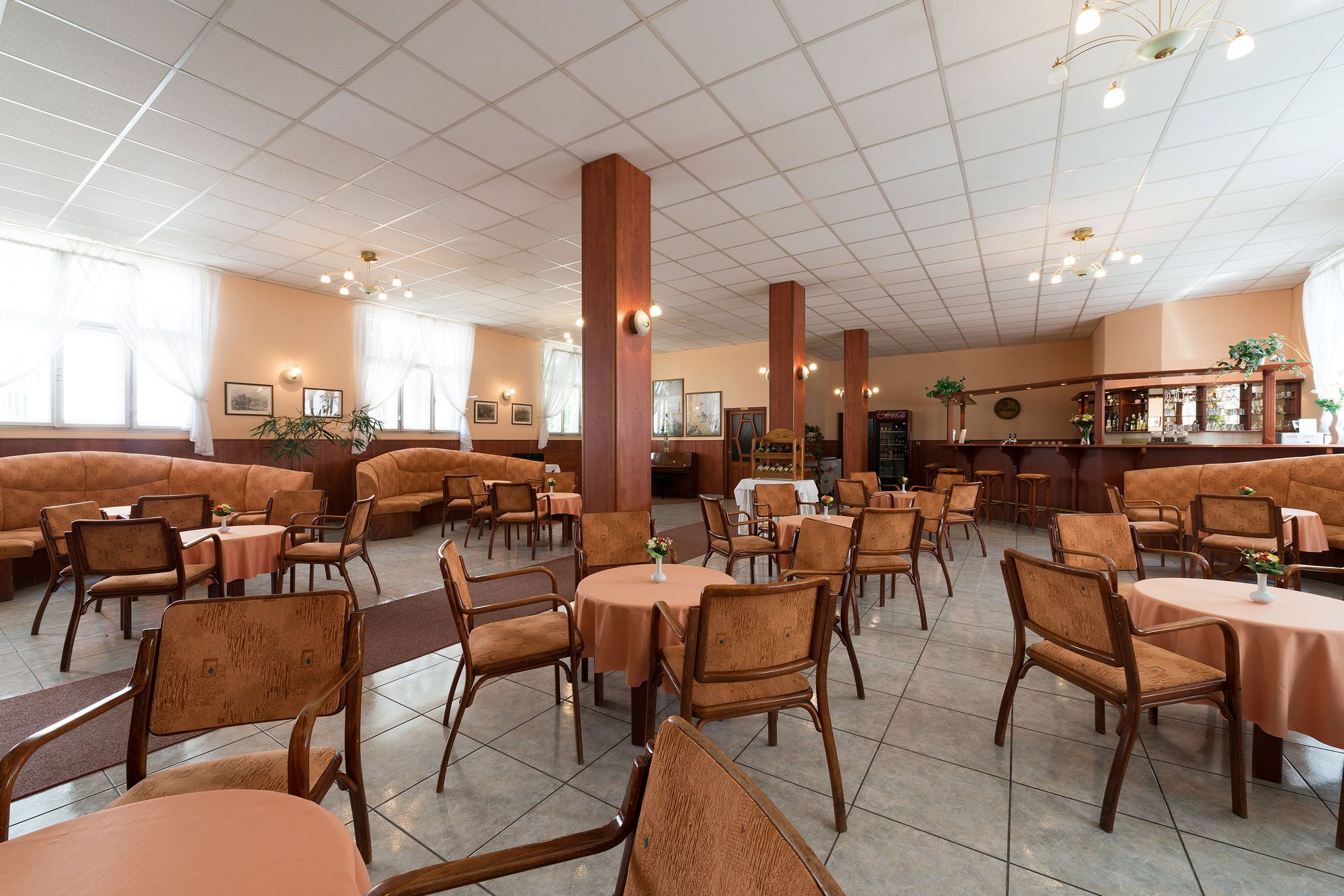 A spacious restaurant with high ceilings, multiple seating areas including booths and tables, and a bar counter.