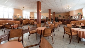 Un restaurante espacioso con techos altos, varias zonas de estar con cabinas y mesas, y una barra.