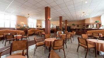 A spacious restaurant with high ceilings, multiple seating areas including booths and tables, and a bar counter.