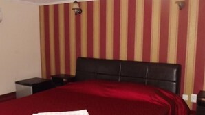 Ein Hotelzimmer mit gestreifter Tapete, einem schwarzen Kopfteil und einer roten Bettdecke.
