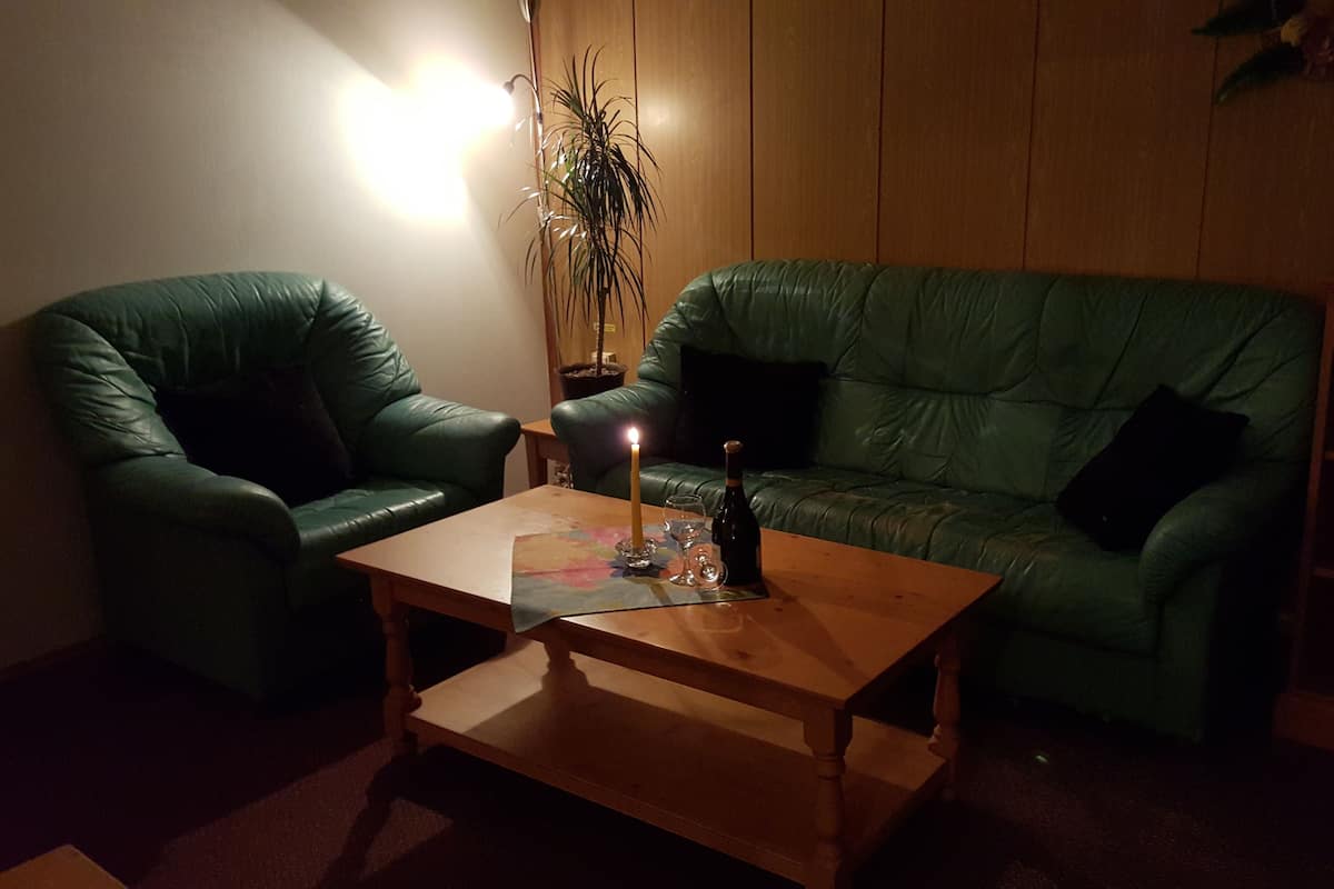 A cozy living room with a green leather sofa, a wooden coffee table, and a lit candle.