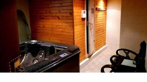 Uma sala de sauna com paredes de madeira, um banco e um painel de controle.