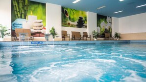Une piscine intérieure dotée d’un indicateur de profondeur, de chaises longues et d’œuvres d’art murales.