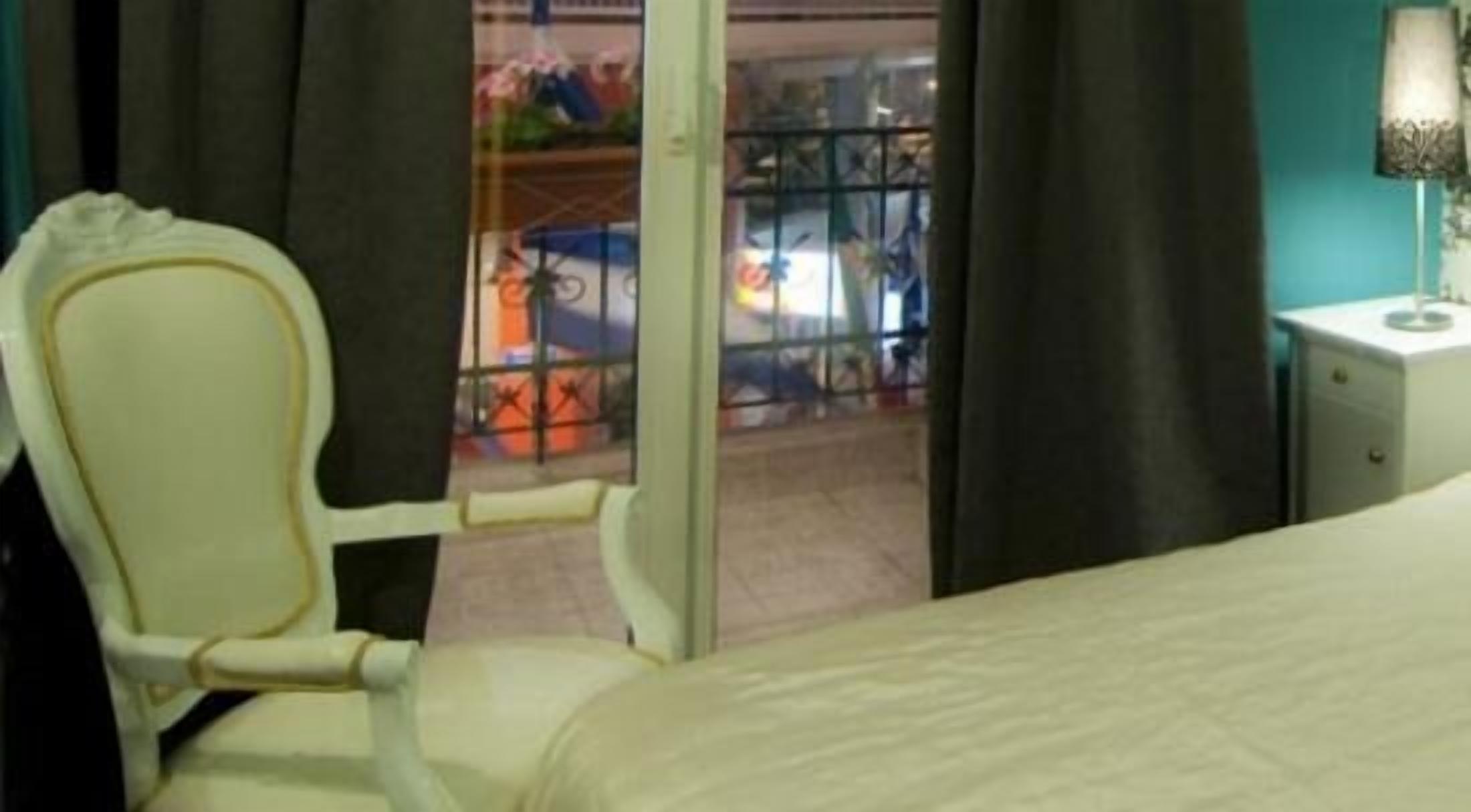 Habitación de hotel con cama, una silla, una mesita de noche y vistas a un área de almacenamiento con bicicletas.