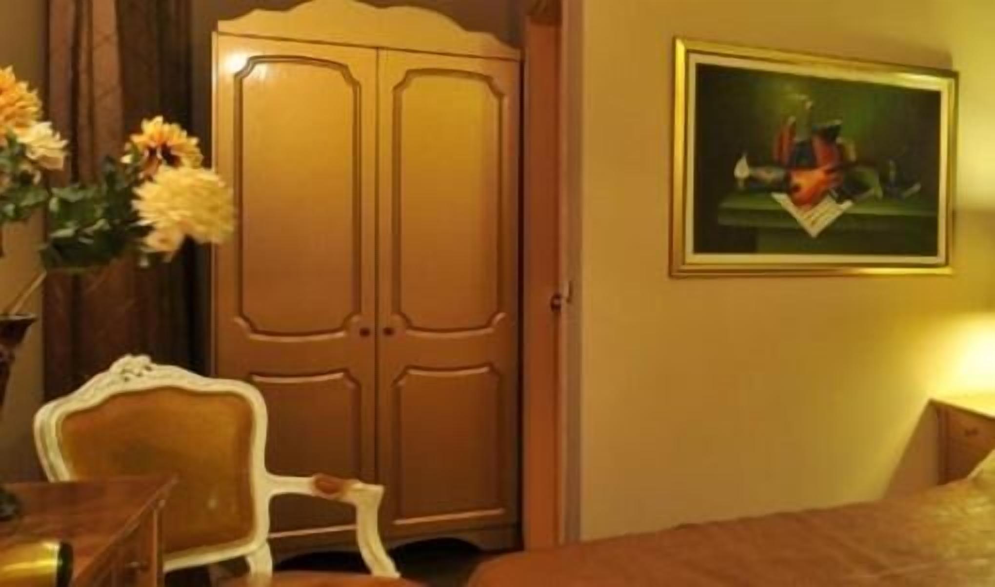 Una stanza con un armadio in legno, un quadro appeso al muro e una sedia bianca.