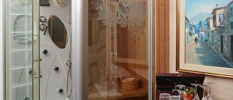 A modern bathroom with a glass-enclosed shower, a vanity with a mirror, and a framed painting on the wall.