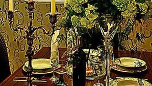 Une table à manger décorée avec des bougies, un vase de fleurs et des assiettes.