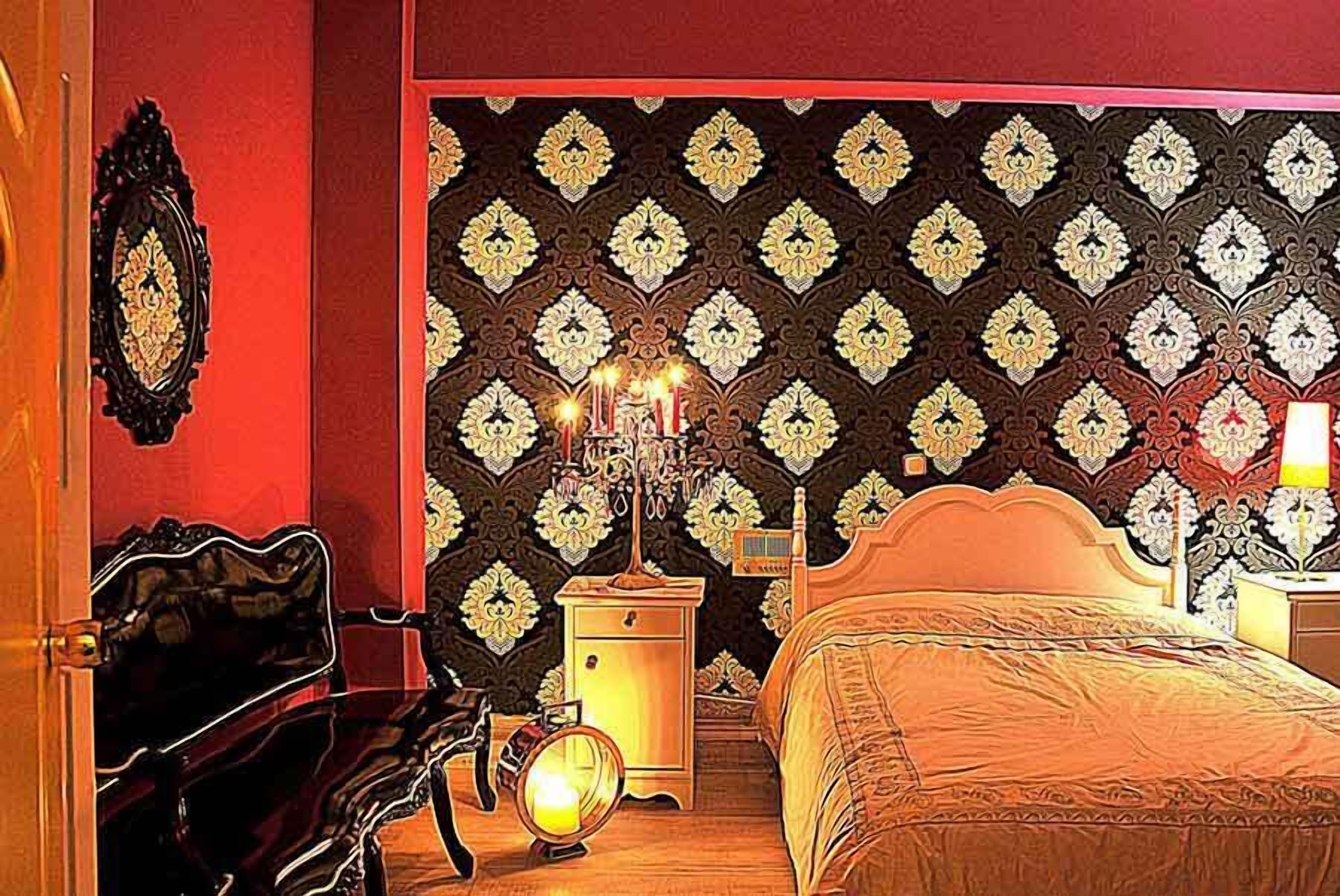 A bedroom with a patterned wallpaper, a bed, a nightstand, and a dresser.
