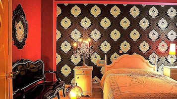 A bedroom with a patterned wallpaper, a bed, a nightstand, and a dresser.