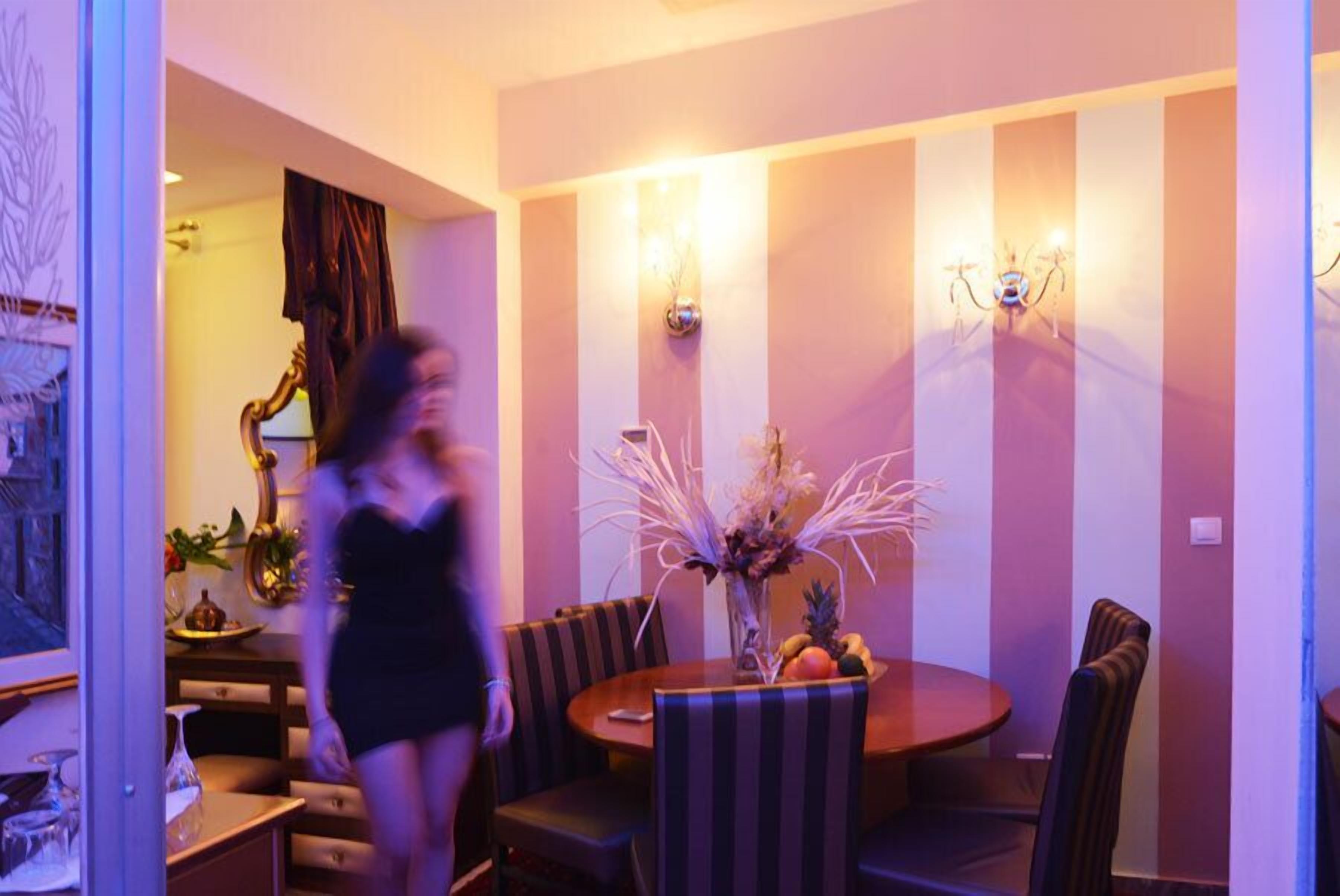 A dining area with a round table, striped chairs, and wall-mounted lights.