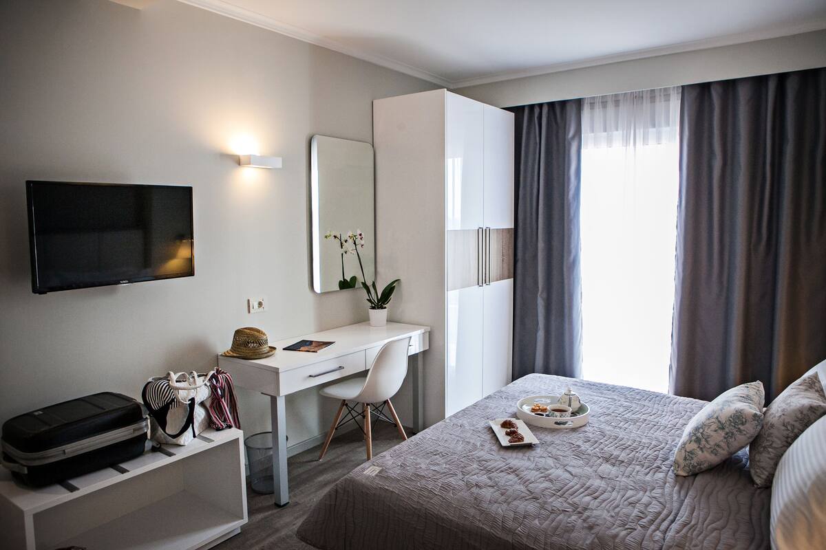 Hotelkamer met een bed, een bureau, een televisie, een kledingkast en een raam met gordijnen.