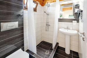 Een moderne badkamer met een douche, wastafel en houten plafond.