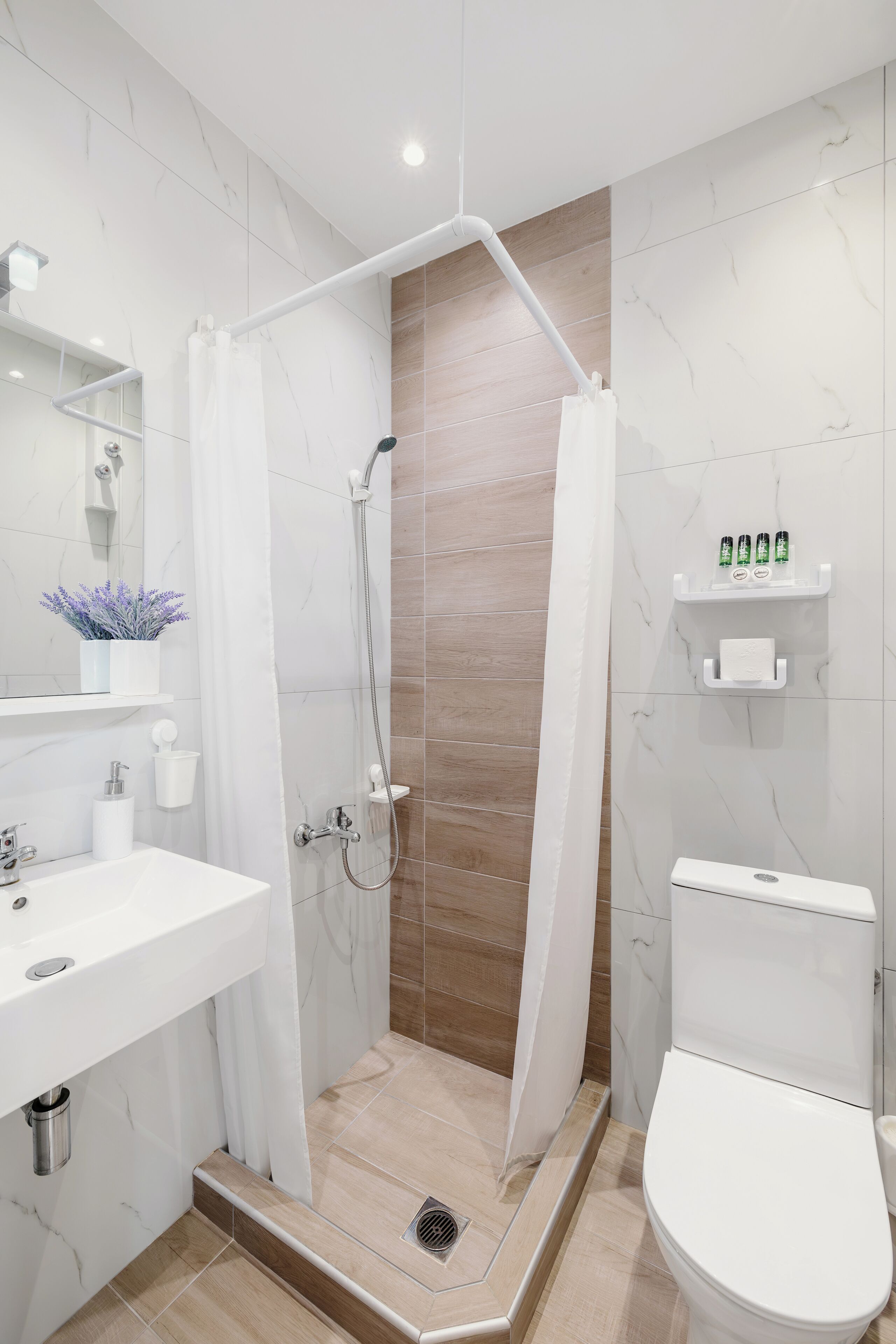 A modern bathroom with a shower, toilet, sink, and a mirror.