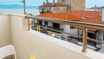 A balcony with a table and chairs, overlooking a historic building and the sea.