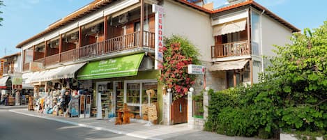 A two-story building with a green awning, a balcony, and a sign for 'Oliva Tiles'.