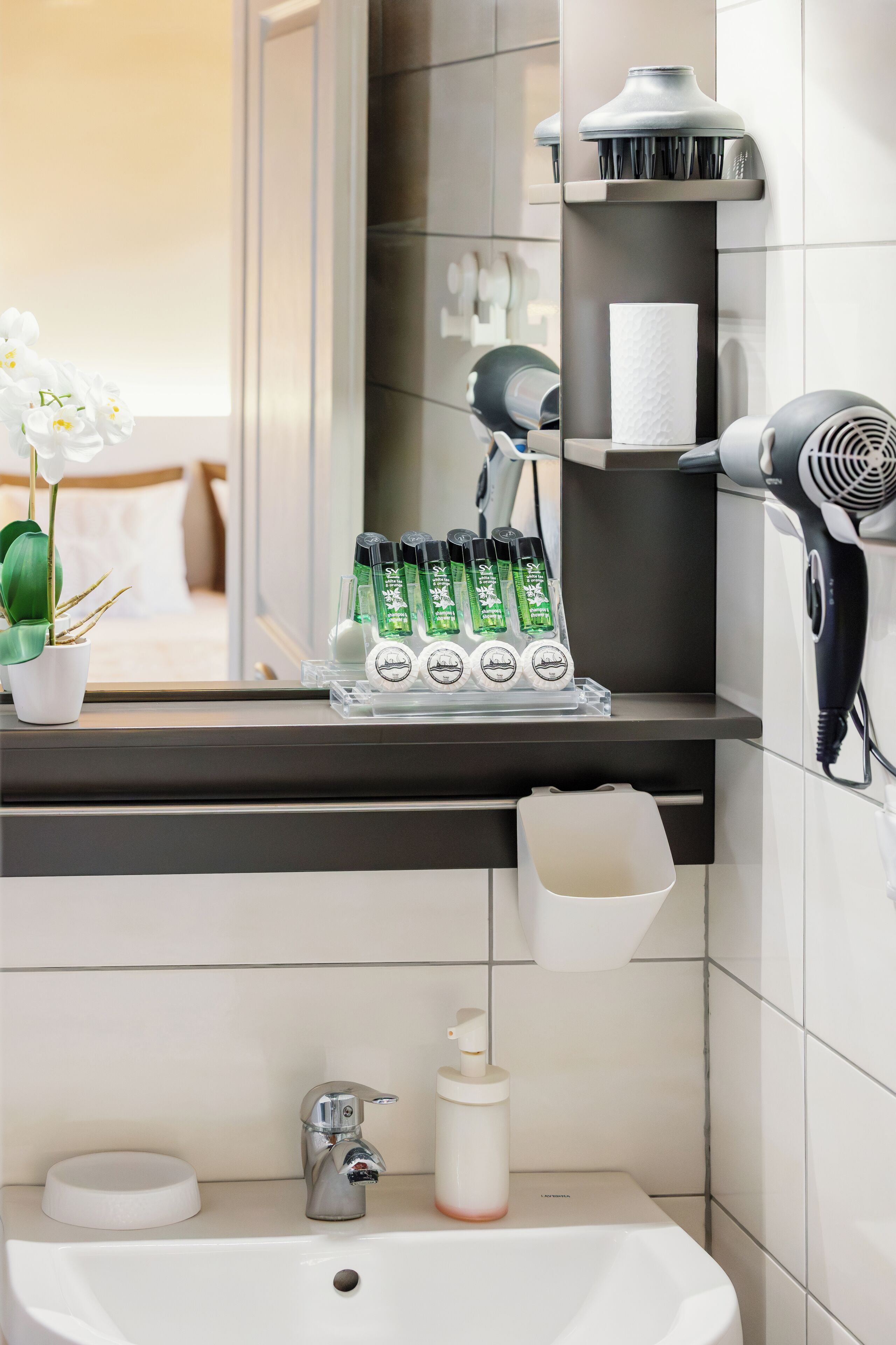 A bathroom with a sink, mirror, and toiletries.