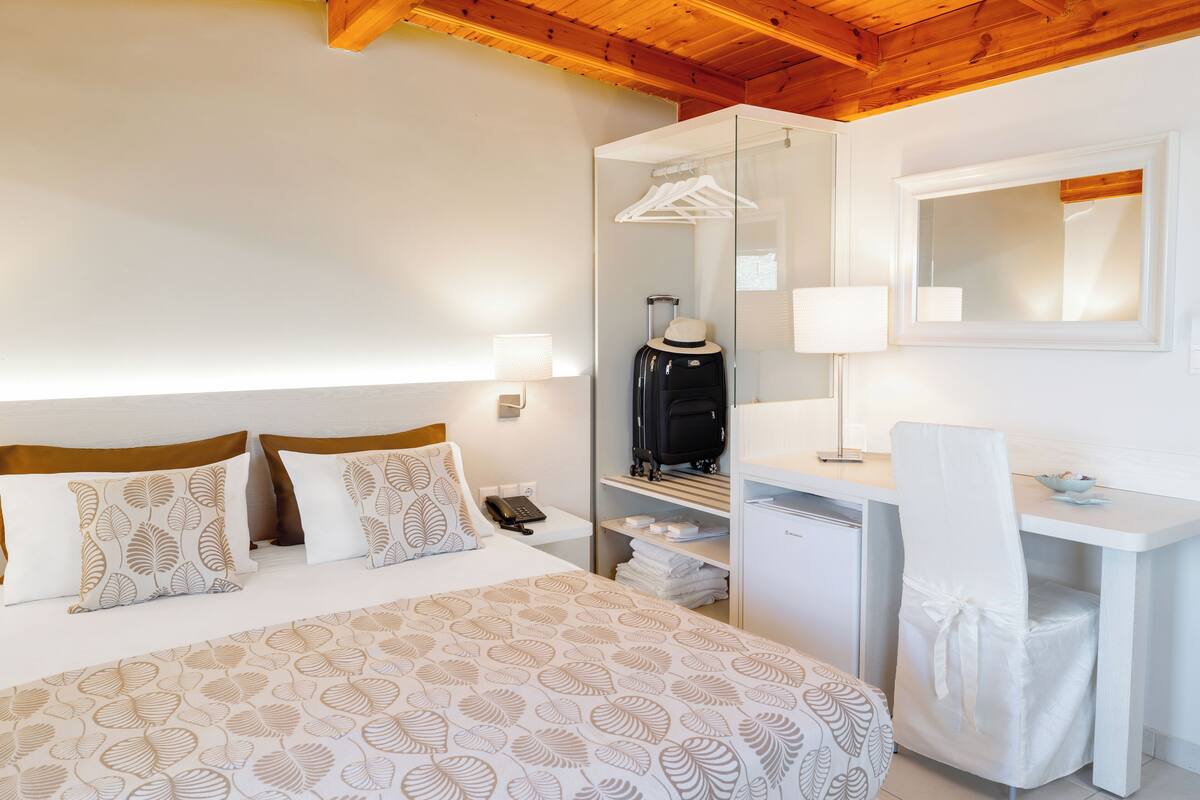A hotel room with a bed, a desk, a mirror, and a wardrobe.