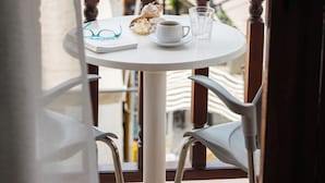 Een balkon met een tafel gedekt voor twee personen, een stoel en uitzicht op zee.