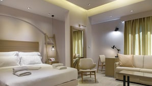 A modern hotel room with a large bed, a sofa, a desk, and a chair. - Hotel Pyrgos Boutique & Suites (Aristotelis)