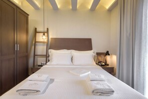 Un lit bien fait avec deux oreillers, une table de chevet avec une lampe, une armoire en bois et une échelle appuyée contre le mur.