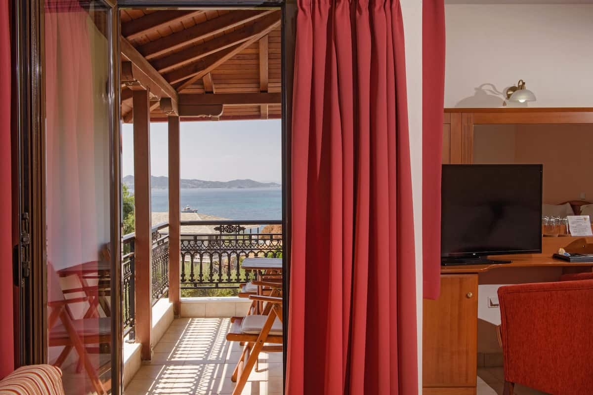A balcony with a wooden pergola, a TV, and a table with chairs.