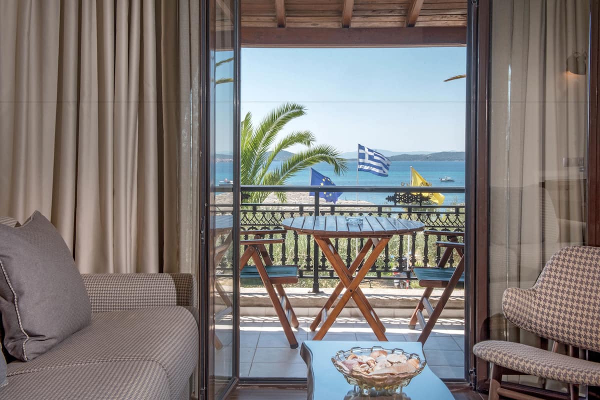 A balcony with a view of the sea, a table with a bowl, and two chairs.