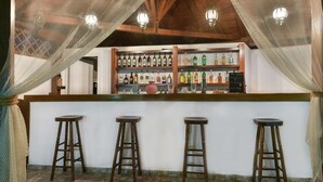 A bar area with wooden beams, a white counter, and four stools. - Hotel Pyrgos Boutique & Suites (Aristotelis)
