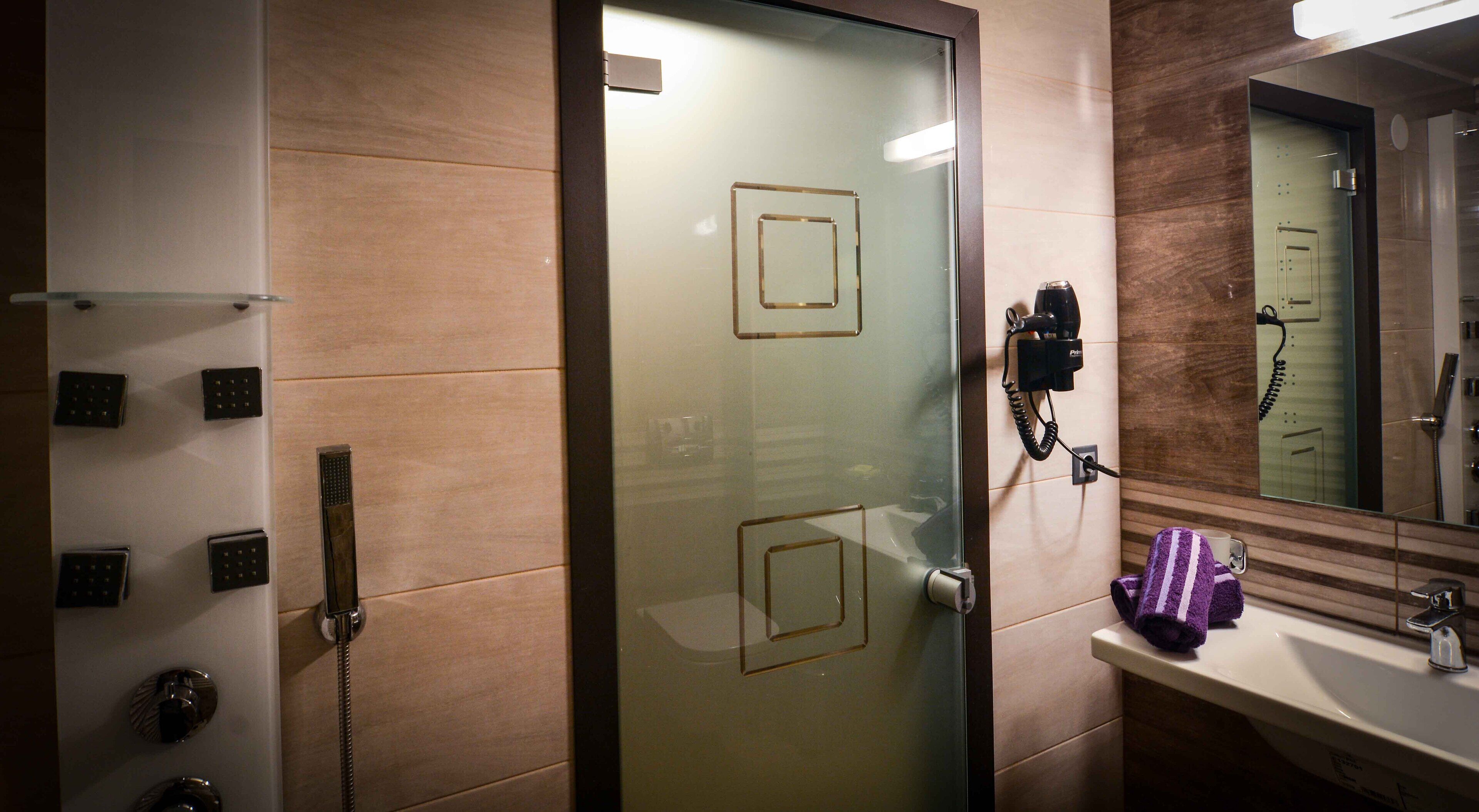 Un baño moderno con puerta de cristal, un secador de pelo y un perchero para toallas.