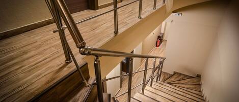 A multi-level wooden staircase with metal railings and a fire extinguisher on the lower landing.