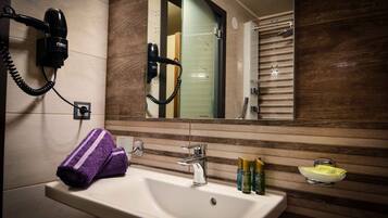 A bathroom with a sink, mirror, hairdryer, and toiletries.