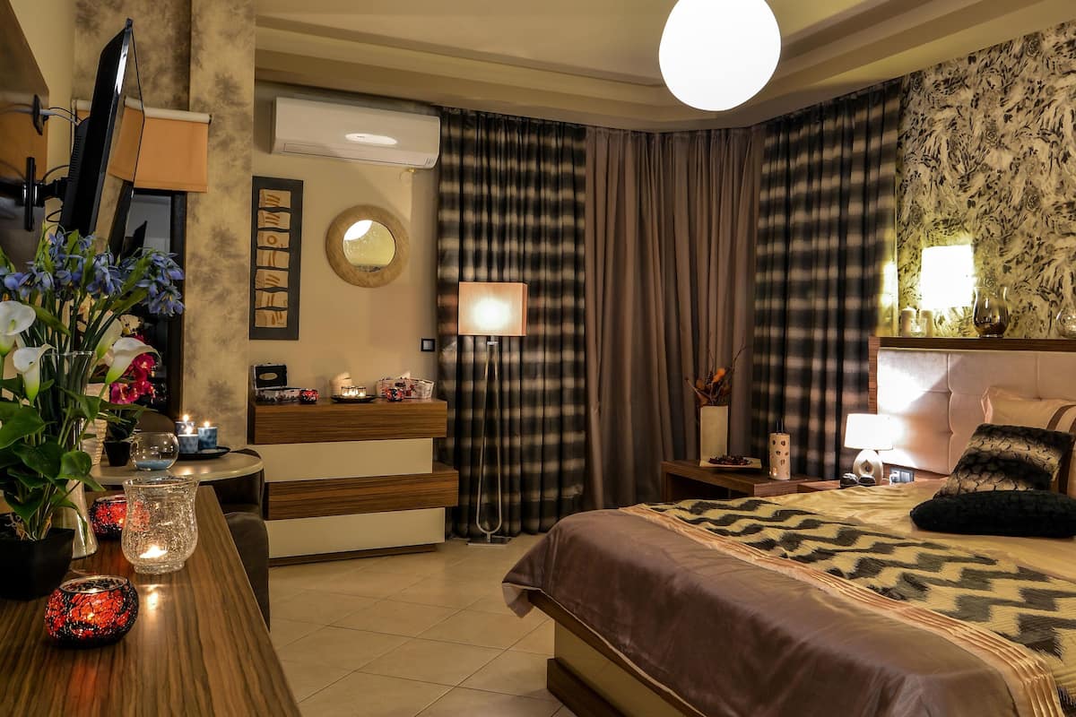 Quarto de hotel com cama, mesa de cabeceira, abajur e um espelho grande.