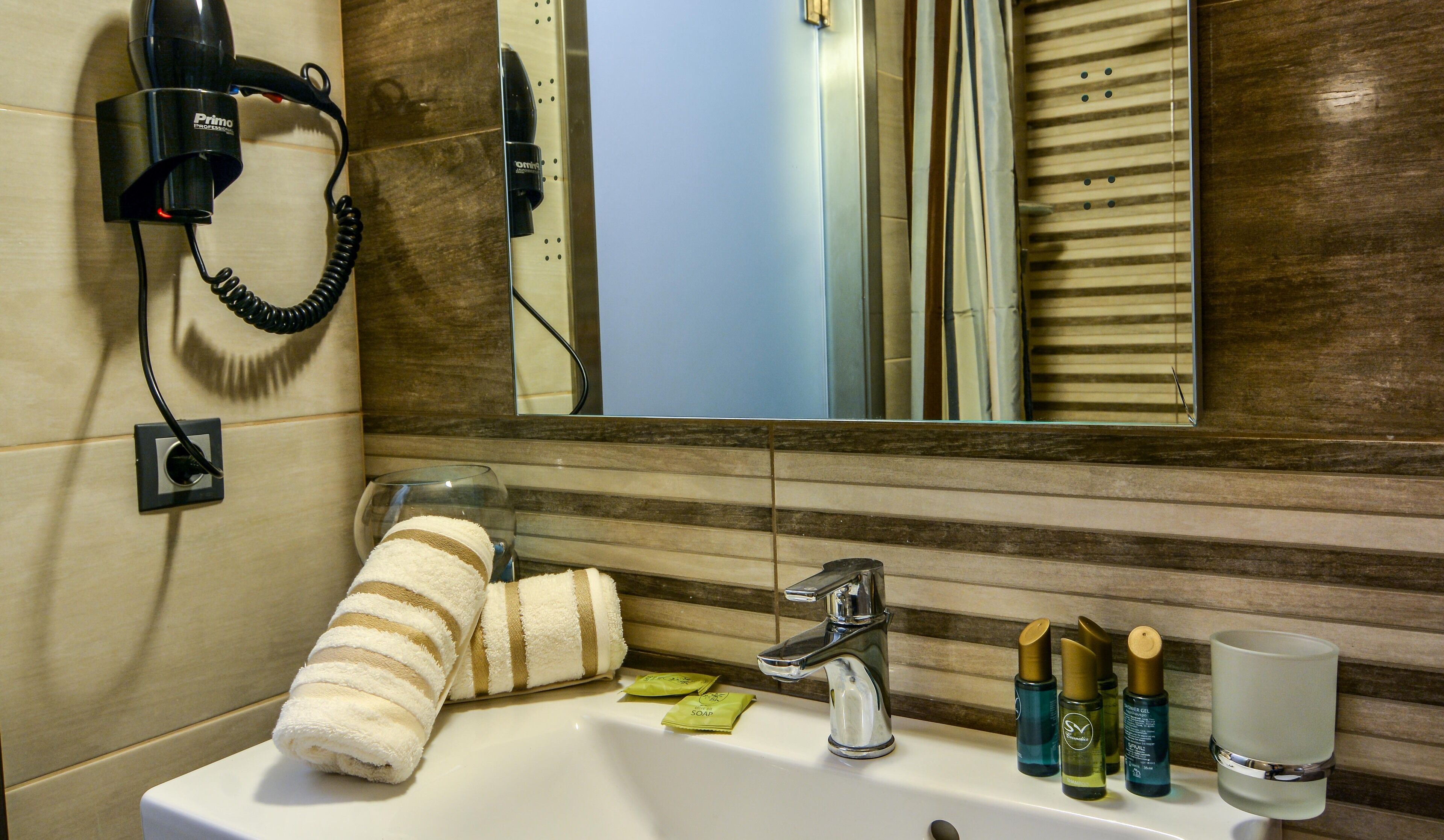 A bathroom with a sink, mirror, towel, hairdryer, and toiletries.