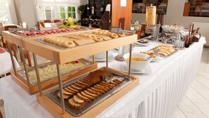 Een buffet met diverse soorten eten en een wijnrek op de achtergrond.