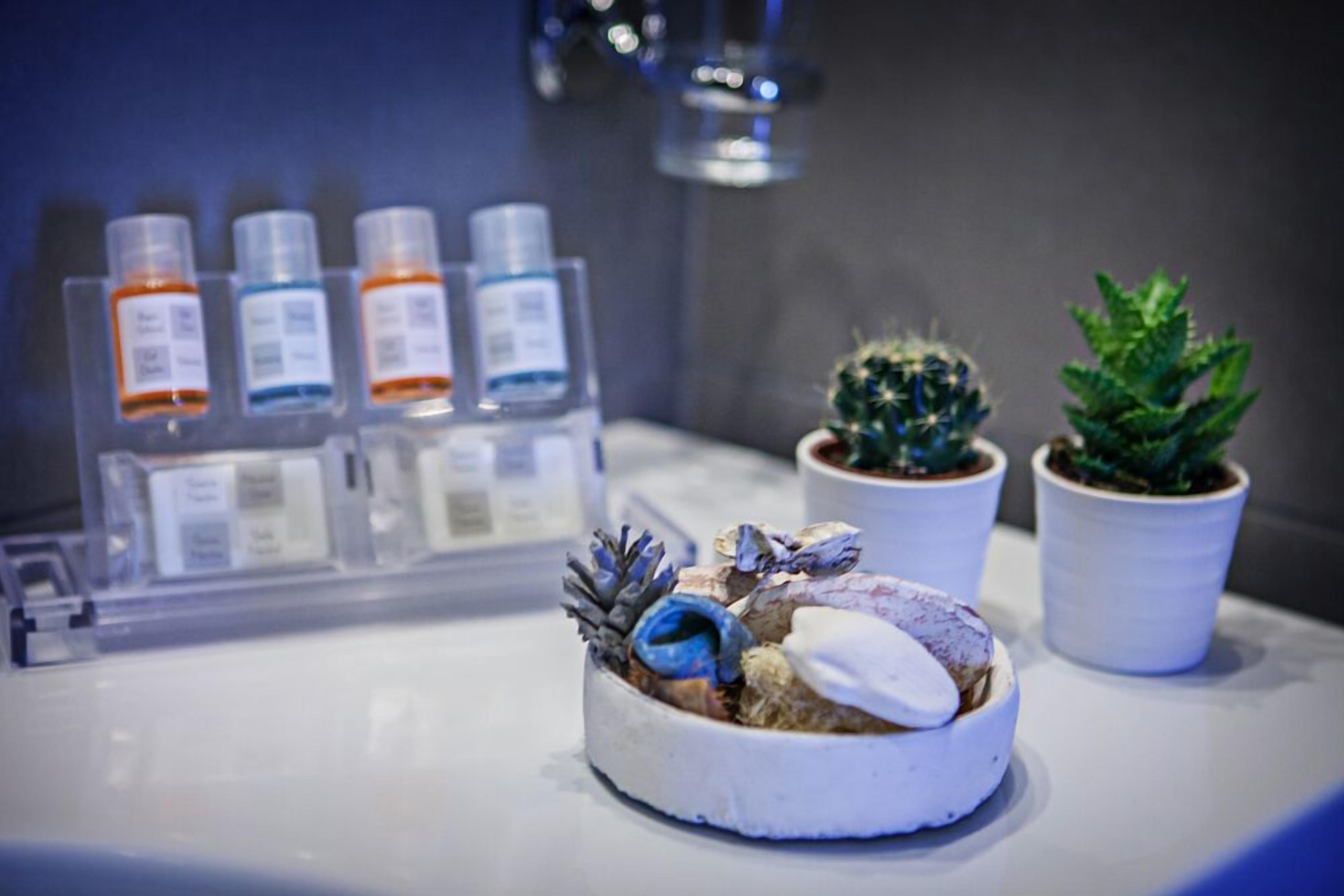 A bathroom with a sink, a small cactus, and a decorative bowl with a pinecone and a blue item.