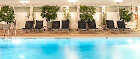 Una piscina al aire libre, sillones reclinables de piscina