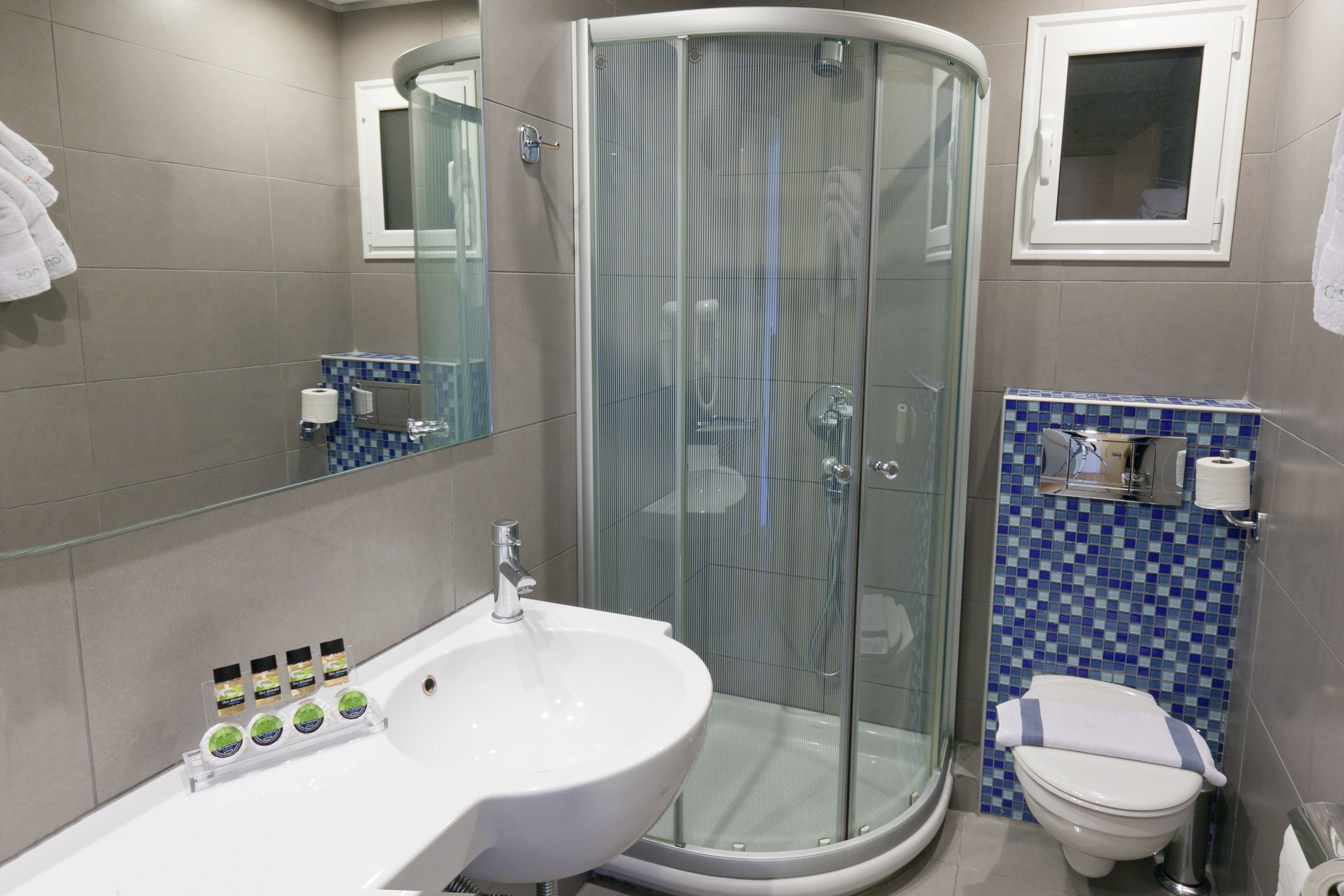 A modern bathroom with a glass-enclosed shower, a white sink with toiletries, and a toilet.