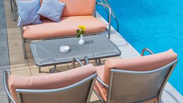 A poolside area with lounge chairs, a table, and a small table with a vase of flowers.