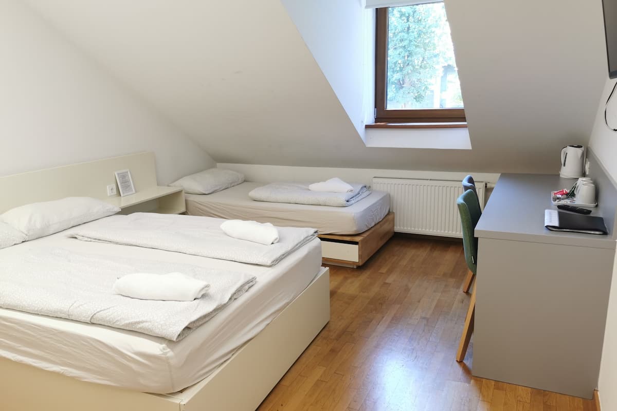 Une petite chambre moderne avec deux lits, un bureau et une fenêtre.