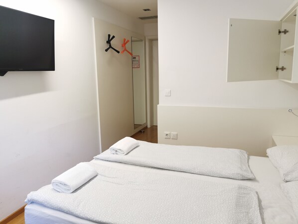 Hotelkamer met een bed, een televisie, een spiegel en een deur met kapstok.