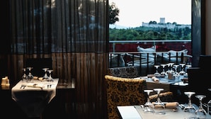 Een restaurant met gedekte tafels, met uitzicht op een kasteel en groen.