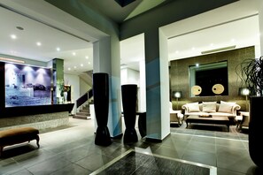 Relax in the hotel lobby, featuring a large TV, comfortable seating area, and staircase to upper floors.
