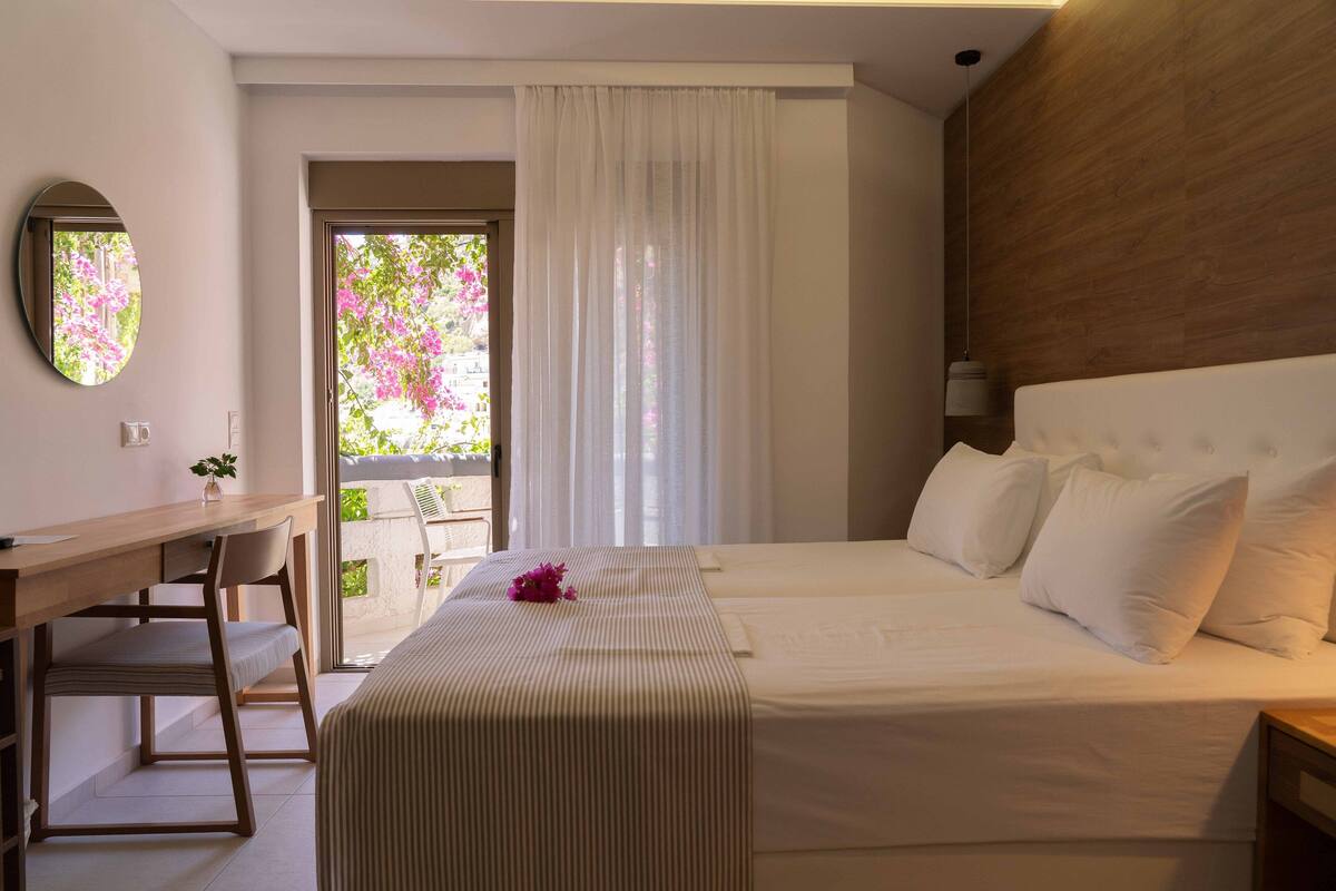 A bedroom with a bed, bedside table, and a desk with a chair.