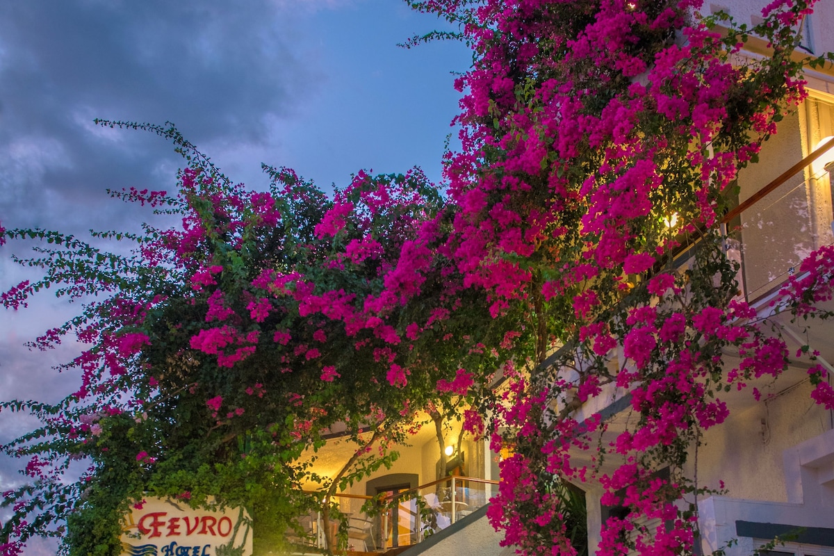 A hotel entrance with a staircase, a reception sign, and bougainvillea flowers.