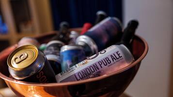 A bowl containing a can of Sol, a bottle of London Pub Ale, and other items.