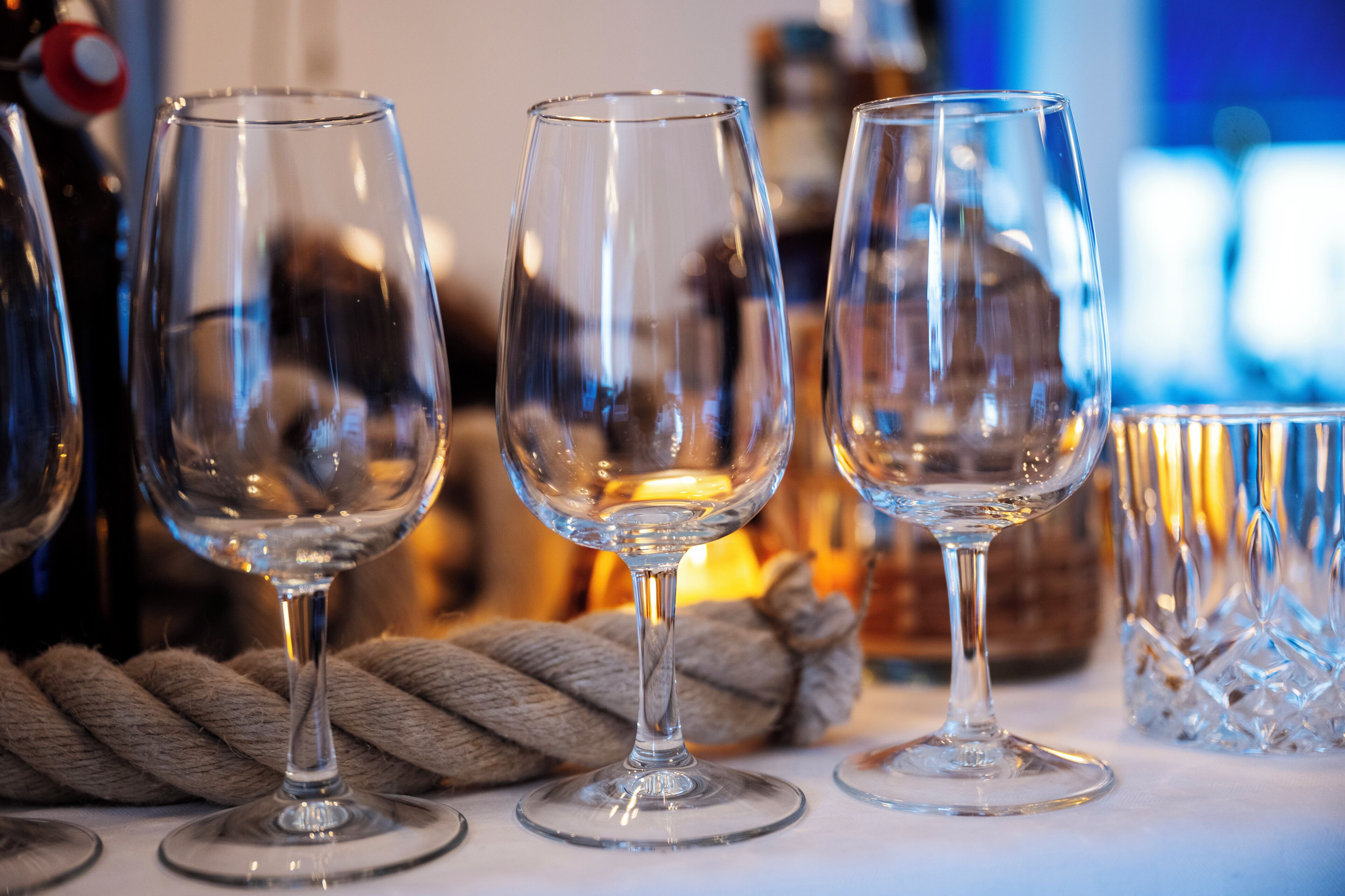 Three empty wine glasses on a table with a rope and a crystal decanter in the background.