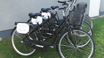A bicycle with a basket and a sign attached to it, parked on grass.