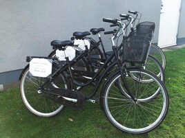 Una bicicleta con una cesta y un cartel, estacionada sobre el césped.