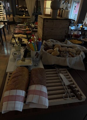 A buffet table with various food items, including bread, pastries, and condiments.