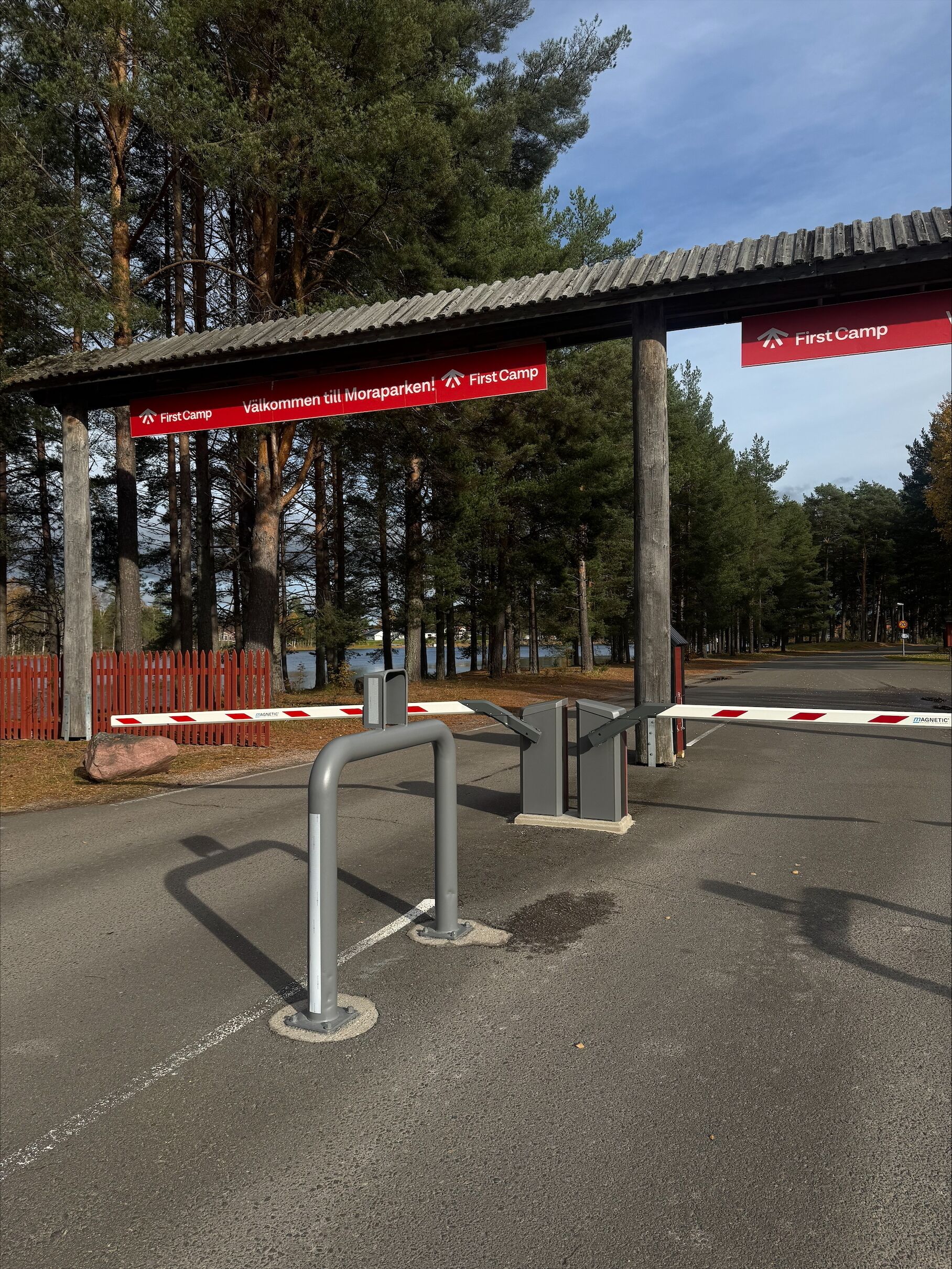 Un área de estacionamiento con un letrero rojo que indica las direcciones hacia 'First Camp' y 'Välkomeri till Moraparken'.