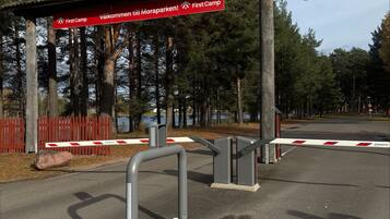 Un área de estacionamiento con un letrero rojo que indica las direcciones hacia 'First Camp' y 'Välkomeri till Moraparken'.